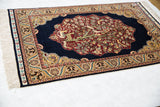 Angled view of a vintage Hereke rug highlighting the lustrous silk pile of the pictorial design.