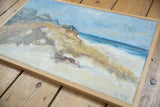 Light blue textured sky and natural wood frame edge of the 'Houses on Beach' painting.