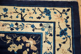 Corner view of vintage Peking rug with scrolling blue and beige floral borders.