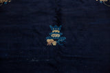 Stylized vase accent in sky blue and beige on a hand-knotted dark blue Peking carpet.
