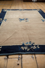 Vintage Peking rug corner, beige field, navy blue floral border, intact side cord, docked fringe.