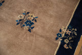 Blossomed blue and ivory floral motifs floating from the navy border onto beige field.