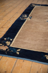 Vintage Peking rug corner: navy border with blossomed motifs, beige field, fabric end.