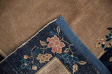 Peking rug corner with beige field, floral navy border, blue fabric end covering.
