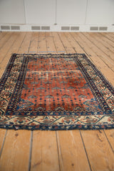 Angled view of Malayer rug, showing rust-red field, allover vinery, and aged patina.