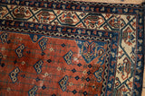 Vintage Malayer rug detail: rust field with blue vinery, intricate beige geometric border.