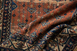 Folded vintage Malayer rug border showing intricate dark blue and rust patterns.