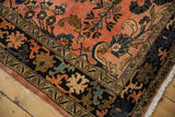 Intricate floral arabesques on the vintage Lilihan carpet's navy border and rose field.