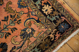 Vintage Lilihan carpet corner with dusty rose field, navy arabesque border, and fringe.
