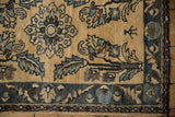 Small human figure and blue floral border detail on a distressed hand-knotted Lilihan rug.