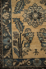 A close-up of a small human figure motif near oversized serrated leaves on a vintage Persian rug.
