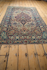 Antique Lavar Kerman rug's curvilinear floral motifs, ivory field, blues, cochineal red, and border.