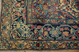 Antique Lavar Kerman rug corner; curvilinear navy and red floral border with even pile wear.