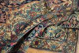 Folded antique Lavar Kerman rug, curvilinear arabesque border and floral field in navy, cochineal, ivory.