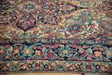 Detail of the antique Lavar Kerman rug's fluid arabesque border in navy, red, and sky blue.