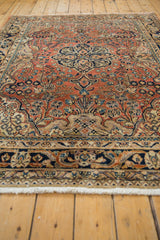 Vintage Persian Arak rug: dusty rose field with navy blue arabesque and floral motifs.