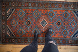 Hand-knotted Vintage Mehreban rug with brick red field, staggered blue lattice, and floral border.