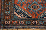 Mehreban rug corner: brick red field geometric lattice, floral brown border, original plain weave fringe.