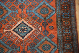 Mehreban rug's main border featuring repeating floral motifs in blue and red.