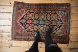 Vintage Lilihan rug, intricate Veramin floral design, starburst border, in navy, blush, and rust.