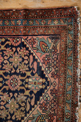 Vintage Lilihan rug corner: navy floral vinery field, rust starburst border, and tattered fringe.