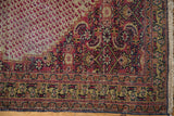 Khorassan rug corner showing intricate wine red, gold, and navy borders with fringe.