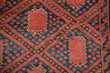 Beshir rug detail: madder red trellis, navy blossom field, showing a foundation hole.