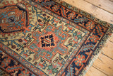 Vintage Heriz rug corner with serrated leaf main border, stylized motifs, and worn fringe.