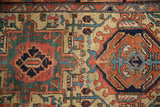 Geometric stylized patterns on the Heriz rug in mallard green, navy, beige, and terracotta.