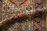 Rolled vintage Heriz rug showing serrated leaf and stylized coral and navy motifs.