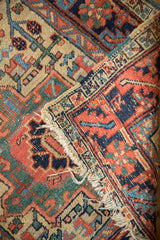 Vintage Heriz rug end, showing tattered fringe, stylized motifs, and polychromatic selvage.