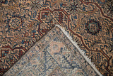 Folded corner of a vintage Malayer rug reveals the fine weave and hand-knotted back.