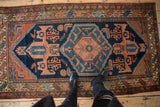 Vintage Mehreban rug corner with navy blue field, terra cotta spandrel, and geometric motifs.