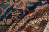 Folded vintage Mehreban rug showing intricate terracotta, navy, and sky blue geometric designs.