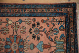 Vintage Lilihan rug corner with dusty rose field, blue borders, and pinwheel floral motifs.