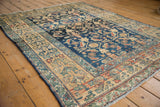 Distressed vintage Lilihan rug close-up: navy blue field with Herati floral motifs, beige border.