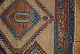 Sharp serrated medallion in blue and copper on a textured camel hair antique Serab rug.