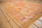 Distressed vintage Oushak rug pile with serrated border and faded ivory, raspberry palmettes.