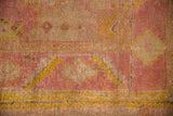 Vintage Oushak rug's distressed angora wool pile texture in mauve, saffron, and ivory.