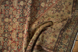 A soft drape highlights the time-softened pile and Herati pattern of an antique Senneh rug.