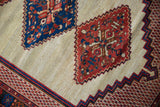 Serrated medallions in sapphire blue and madder red on a hand-knotted ivory field.