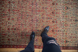 Antique Zuli Sultan rug, allover floral pattern: ivory, tomato red, navy blue, with worn pile under boots.