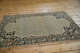 Angled view of antique Farahan Sarouk rug, ivory germinating seed boteh field, navy floral spandrels.