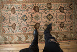 Distressed vintage Mehreban rug's pale blush field with floral blossoms and arabesque motifs.