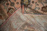 Folded corner of vintage distressed Mehreban rug, showing hand-knotted foundation and worn floral pile.