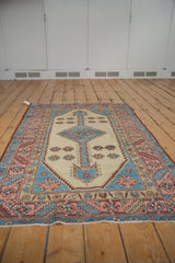 Close-up of distressed Bakshaish rug border showing blush, sky blue serrated leaves and faded pile.