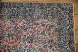 Intricate millefleur pattern and palmettes on a vintage Kerman rug, featuring blush, ivory, and blue tones.
