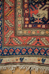 Antique Armenian Karabagh rug corner: navy, coral, ivory border, stylized bird motifs, aged fringe.