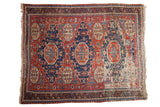 Antique Soumac carpet with triple navy medallions, cherry red field, pinwheel florals, and visible foundation, 7'1