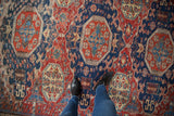 Antique Soumac carpet detail: cherry red, navy blue geometric tribal patterns, exposed foundation.